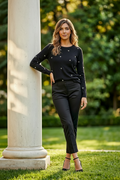 Model wearing a black pearl embellished sweater with subtle front tuck into black tailored trousers